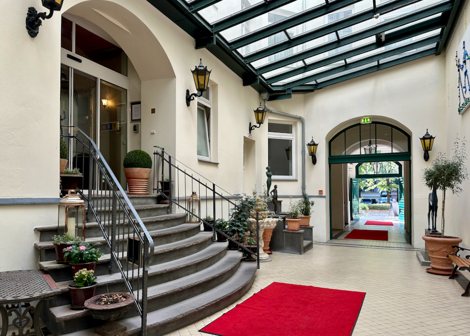 Entrance to a hotel with covered glass roof and potted plants