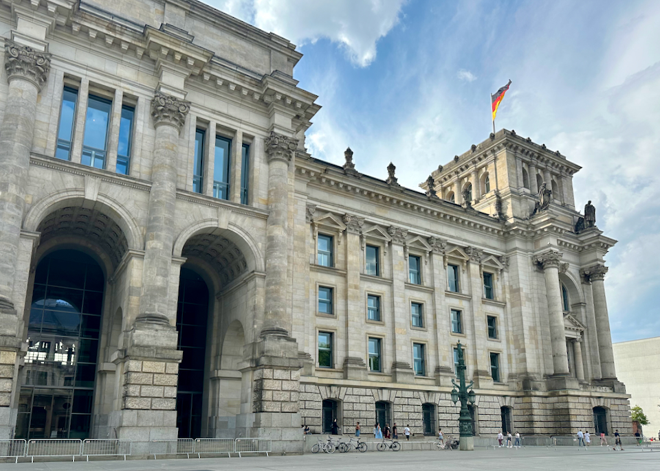 Side view of the Reichstag building in Berlin, with people walking by.
