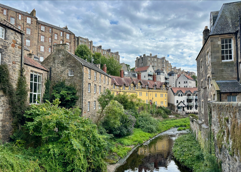 Quaint old Scottish building lining a lushly-banked river 
