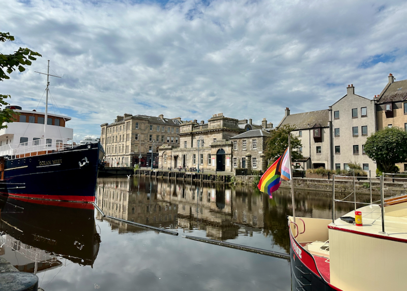 Boat on a river in Scotland, flying a pride flag 