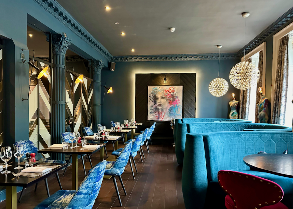Chic hotel restaurant with modern art displayed and striking teal velvet banquette seating
