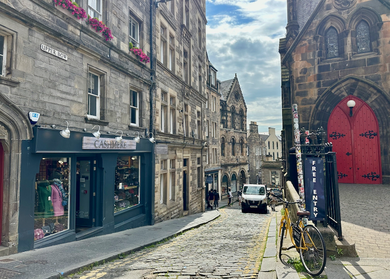 The Royal Mile thoroughfare in Edinburgh, flanked by old stone buildings and shops. 