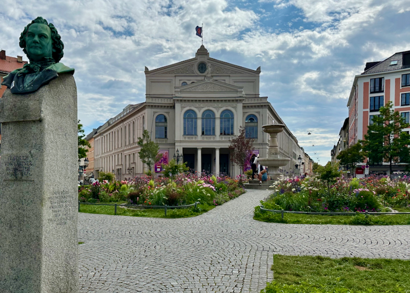 Gravel pathway leading through a garden plaza to a beautiful building