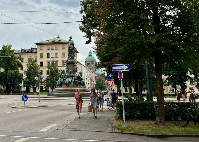 Two women walk along a sidewalk in a posh area of Munich