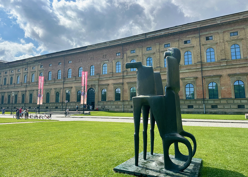Exterior of the Alte Pinakothek Museum in Munich, with a bronze modern sculpture in the foreground. 