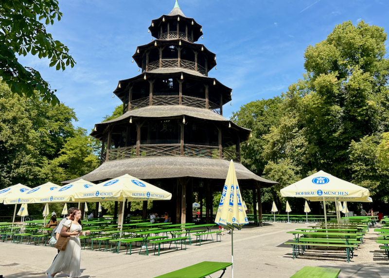 Pagoda-style building in a garden, surrounded by picnic tables.