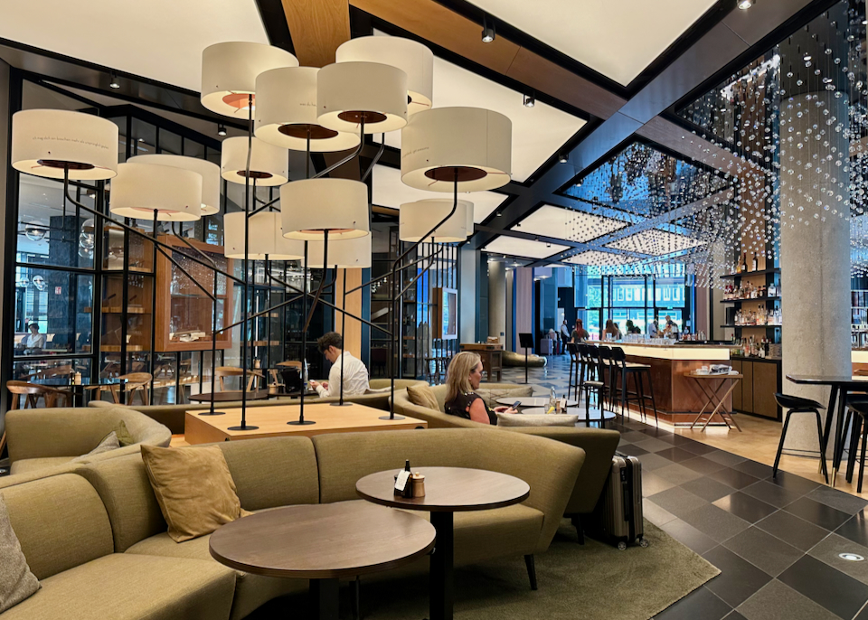 People sit at tables in a posh hotel lobby.
