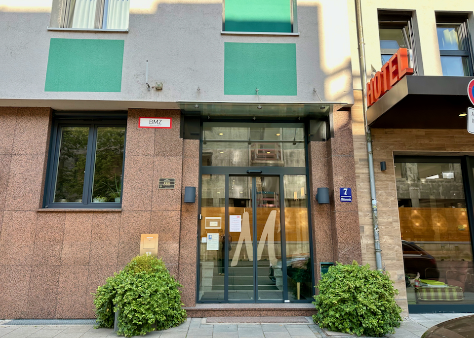 Glass door entrance to a hotel, with the monogram M etched in the door.