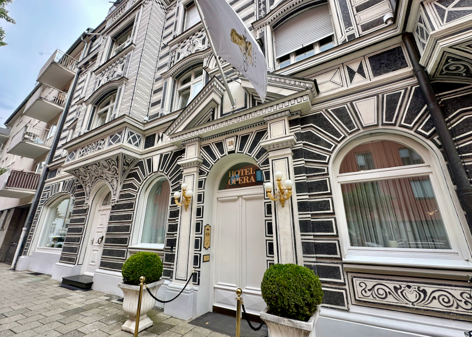 Ornately-painted hotel exterior entrance, flanked by topiaries