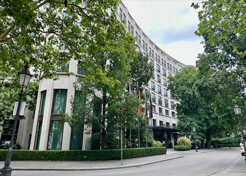Exterior of a curving, white, luxury hotel in Munich