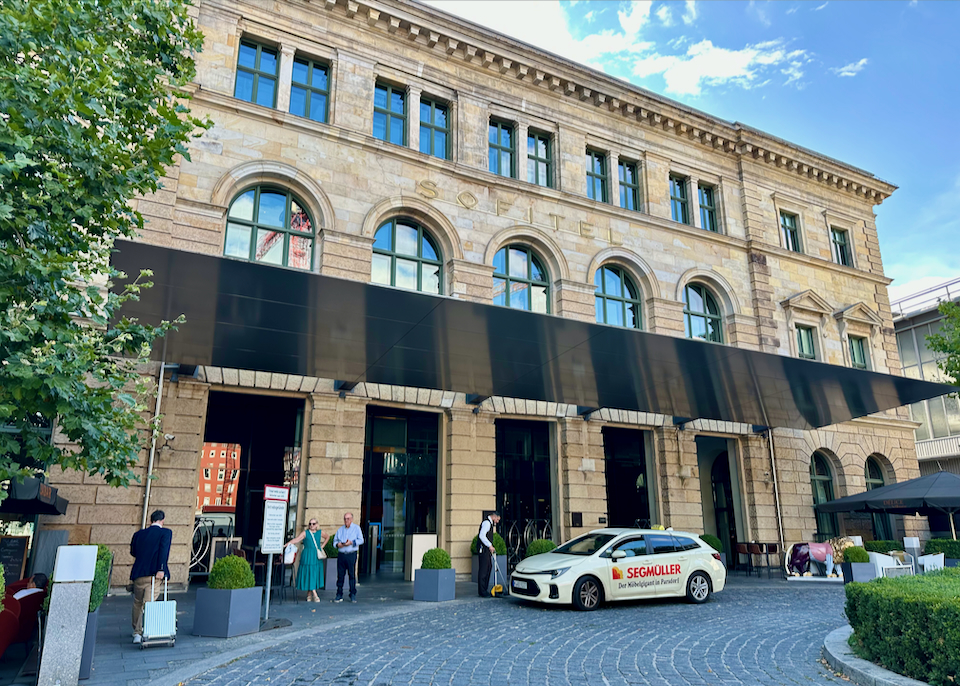 People wait for a valet in the circular drive of a luxury hotel