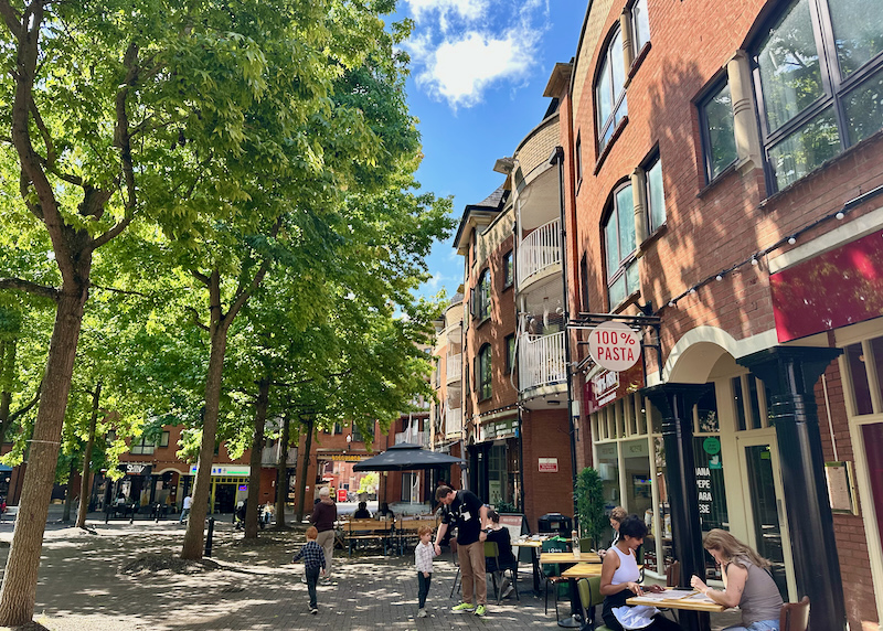 People st at cafe tables in leafy Gloucester Green square in Oxford, England