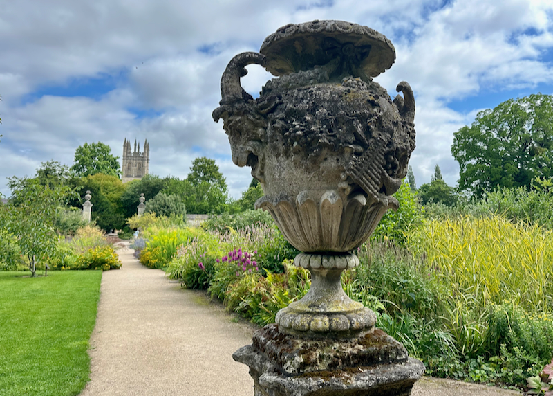 View along a flowery garden path, with a stone urn in the foreground