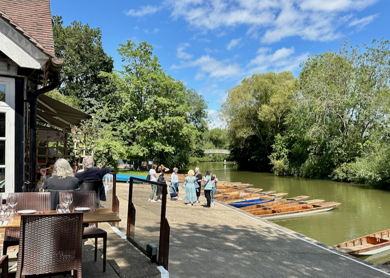 People stand at on the dock of the Cherwell Boathouse in Oxford on a sunny day
