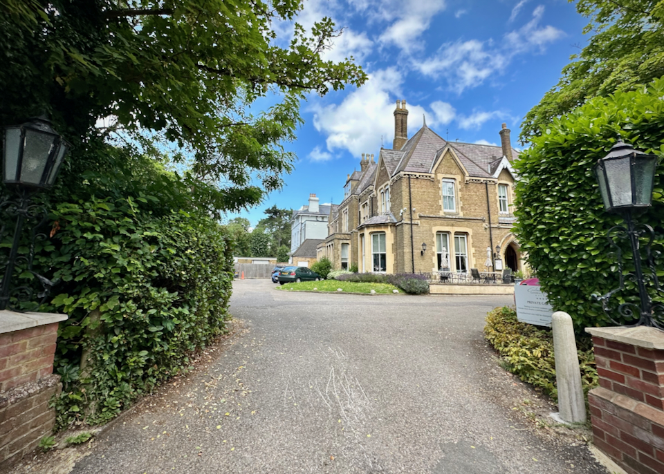 View up a gravel driveway to a stone boutique hotel in England.