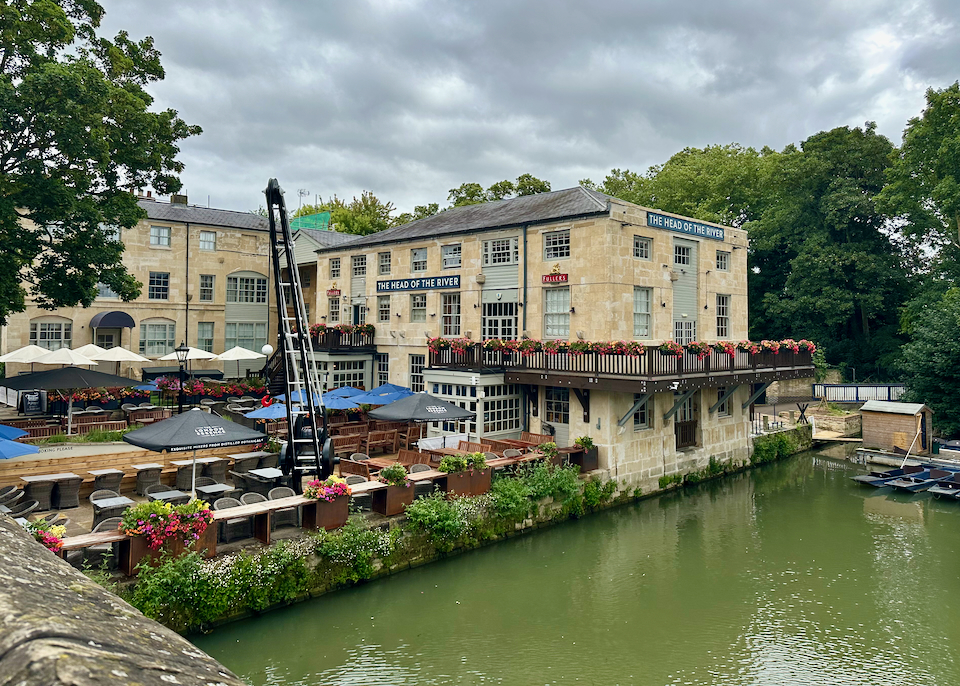 View over a river of a boutique hotel in an old stone building with waterside terrace