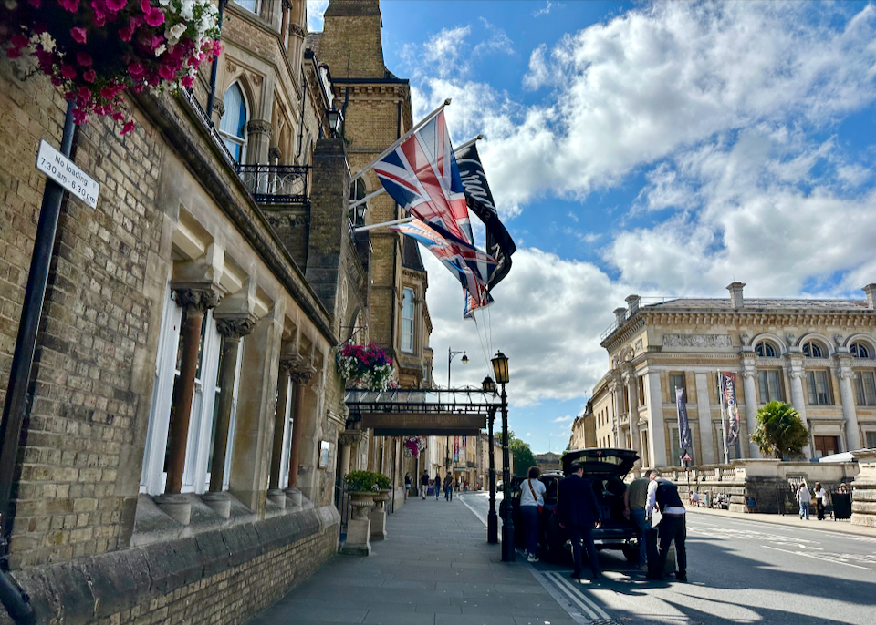 View looking up an elegant street in Oxford, England, past the entrance of a luxury hotel with flags flying in the wind