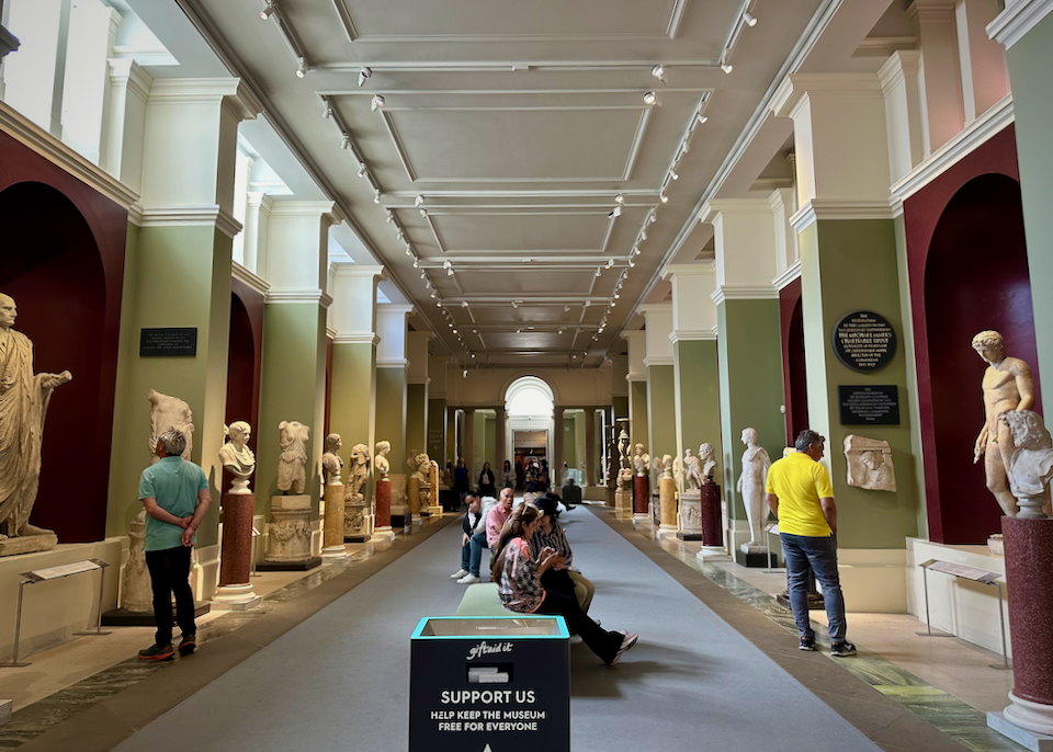 People in a museum look at marble statues.