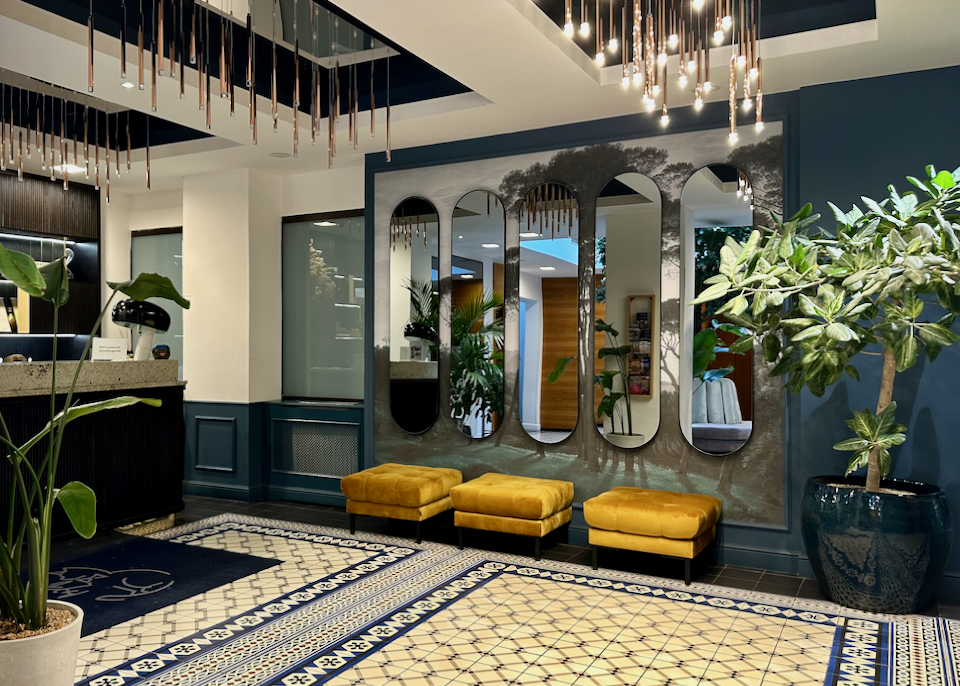 Striking tiled entryway of a hotel lobby, with yellow velvet bench seating.
