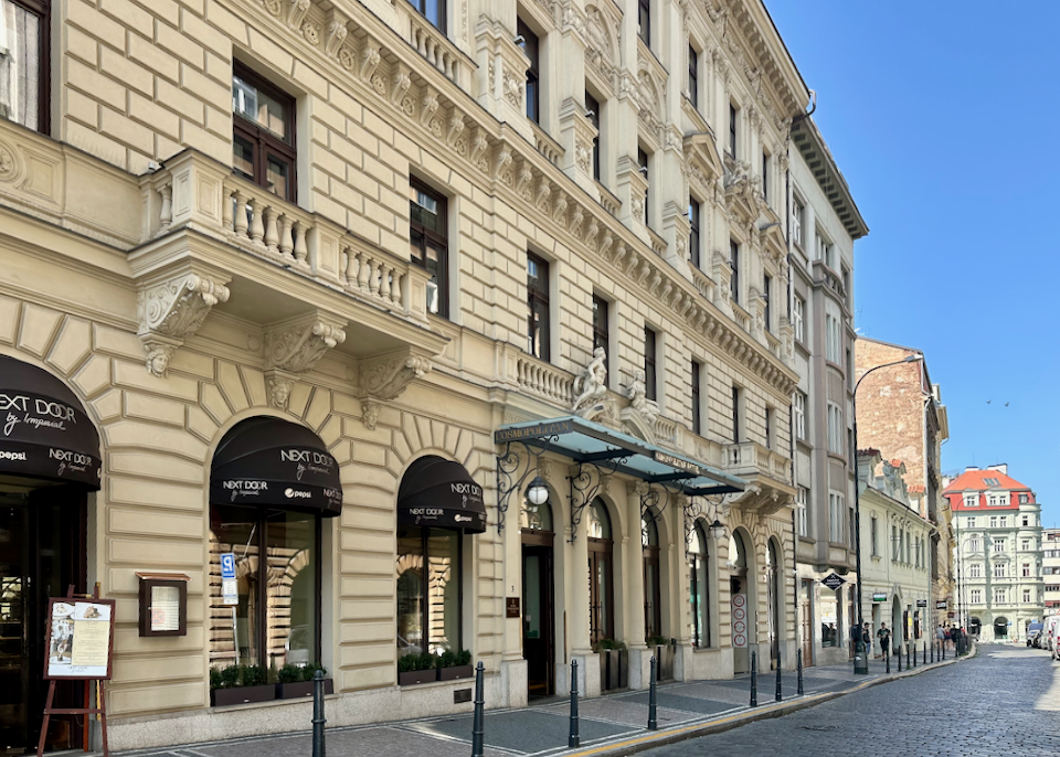 Ornate exterior of a hotel on a narrow street in Prague
