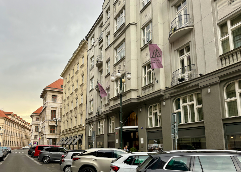 Narrow street of hotels in Prague, lined with car parking