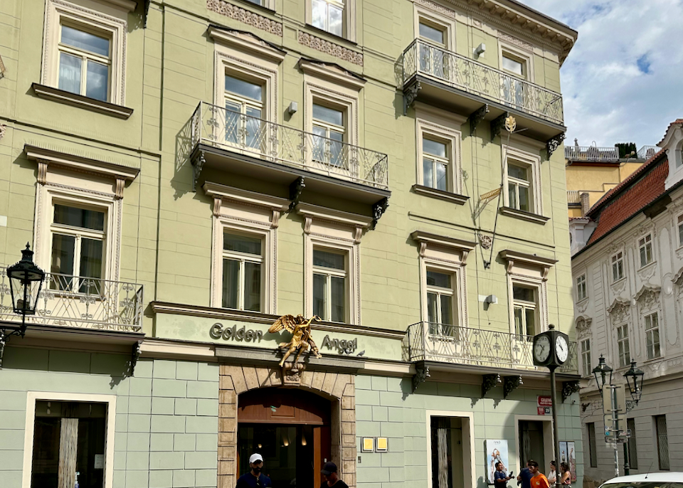 Green exterior of a boutique hotel, with a golden angel statue perched above the doorway