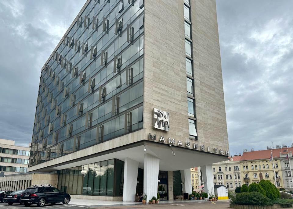 Large glass and concrete hotel building cantilevered over a modern entrance