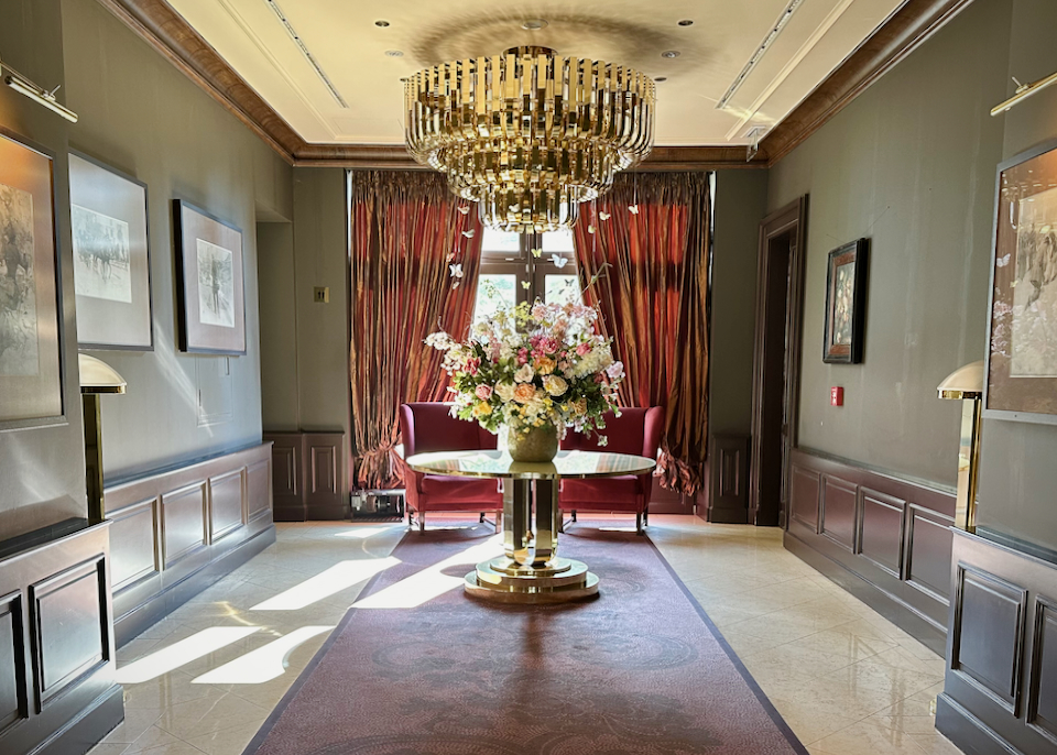 Light streams in through a window into a room showcasing a large floral arrangement