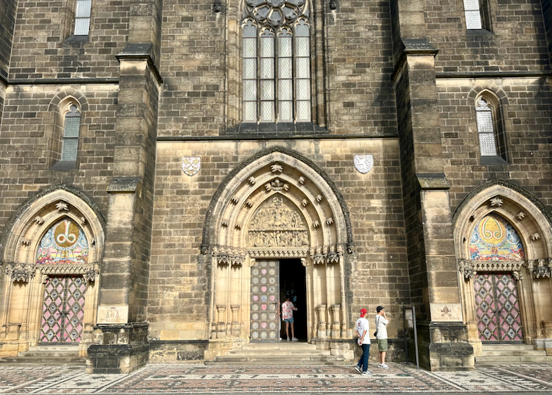 People walk in the open door of a stone cathedral
