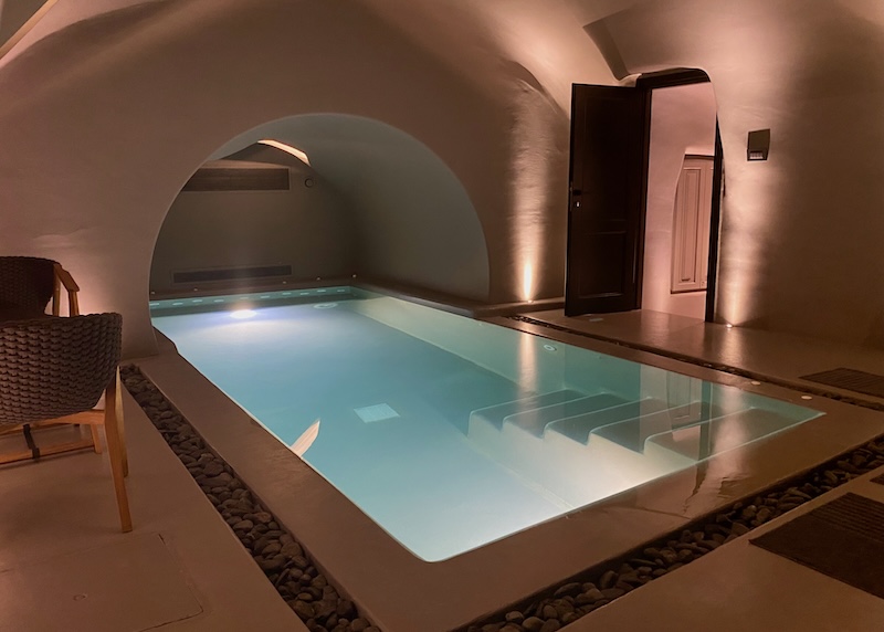 An indoor, cave pool with jets at the far end and soft lighting at Kivotos hotel in Imerovigli.