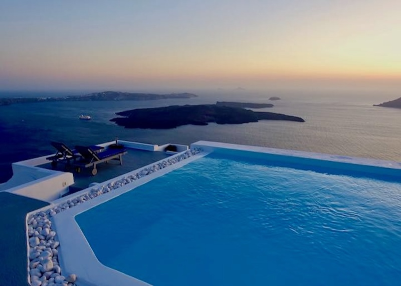 Sunset at the infinity pool of Altana Heritage Suites with views over the caldera, volcanoes, and Akrotiri in Santorini.