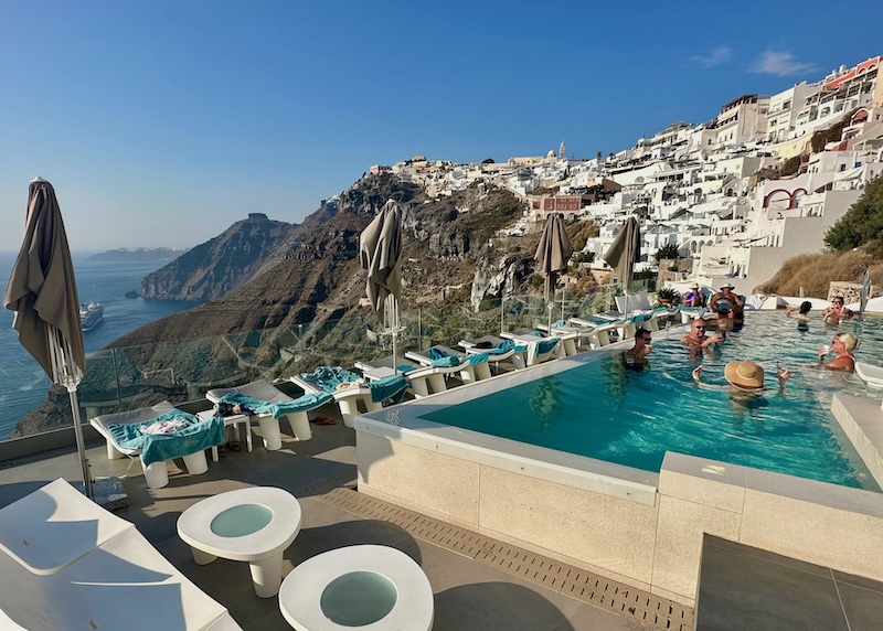 People enjoying cocktails in the infinity pool with a caldera view at Athina Luxury Suites in Santorini.