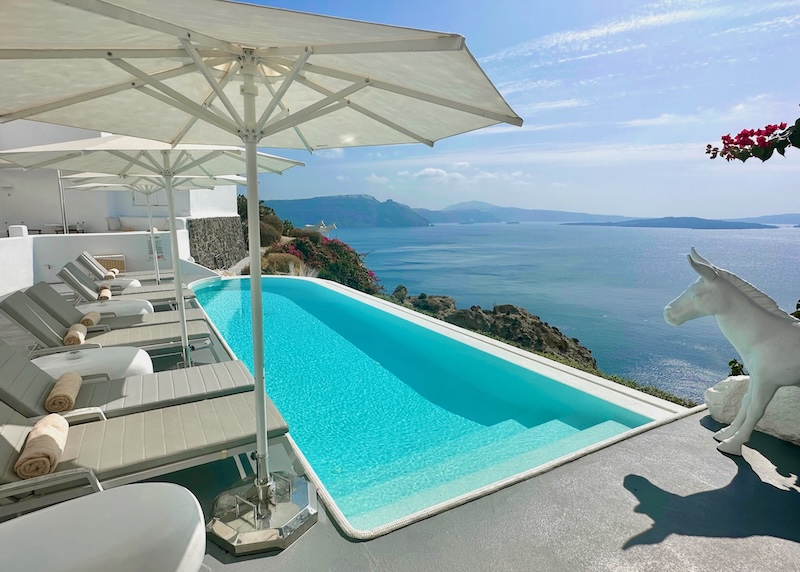 Infinity pool with caldera view and a statue of a donkey at Canaves Sunday Suites in Santorini.