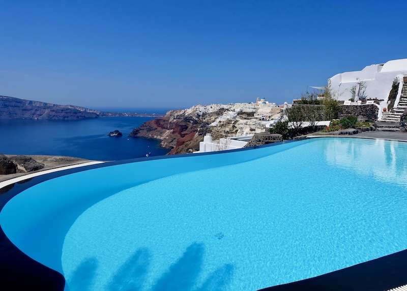 Kidney-shaped infinity pool overlooking the caldera and Thirassia Island at Perivolas Hotel in Santorini.