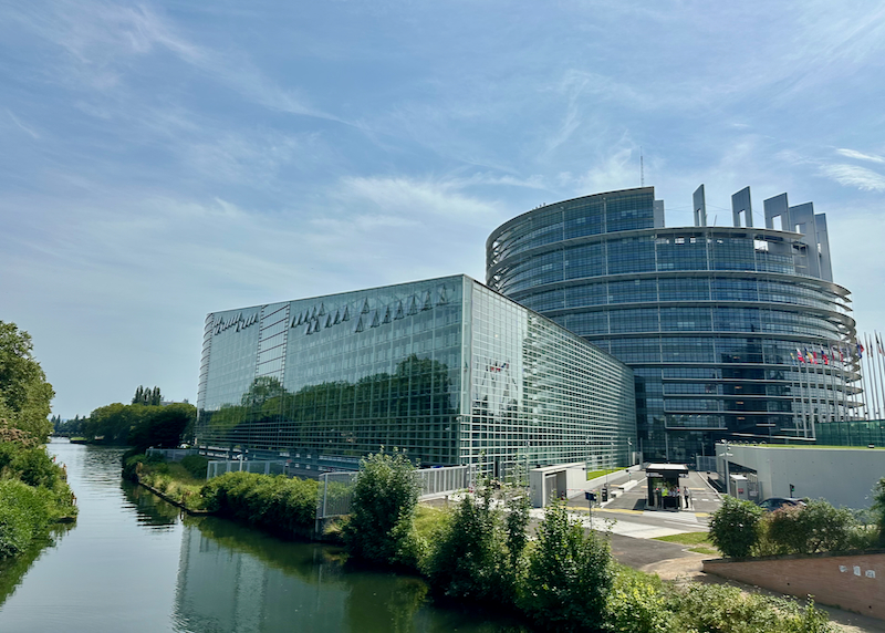 View over a waterway of a glass and steel elliptical building