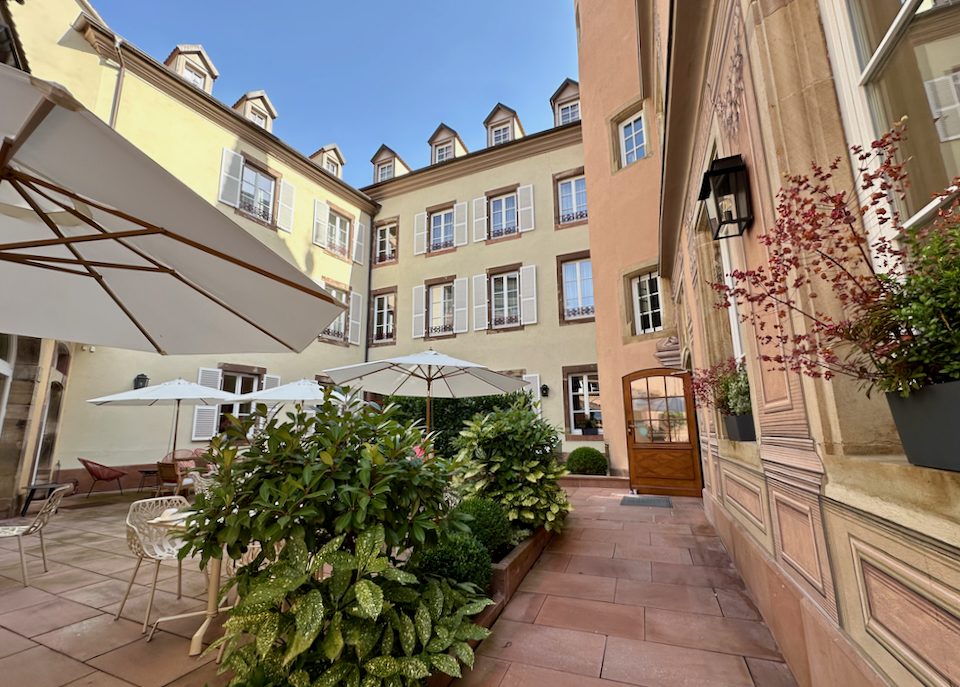 Covered tables on a rustic hotel courtyard on a sunny day.