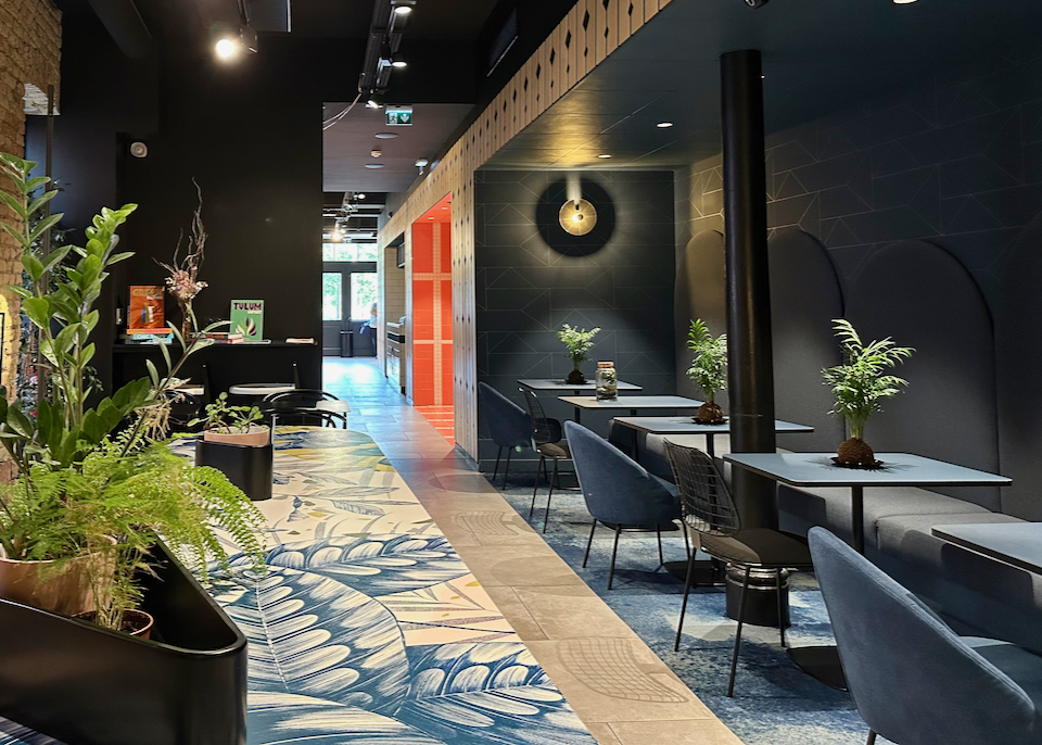 Modern hotel dining area done in moody tones, with dim lighting.