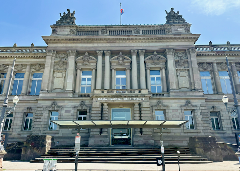 Grand Neoclassical building with a French flag flying on top 