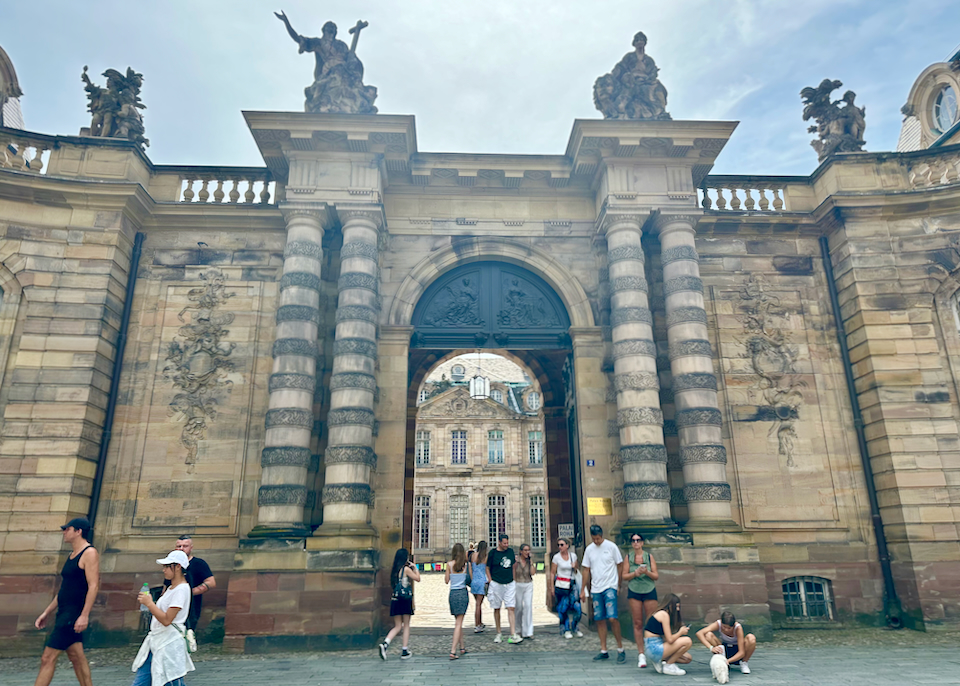 Tourists gathered outside the stone gate of Palais Rohan in Strasbourg