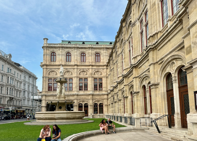 People sit on the steps of the Staatsoper opera house in Vienna