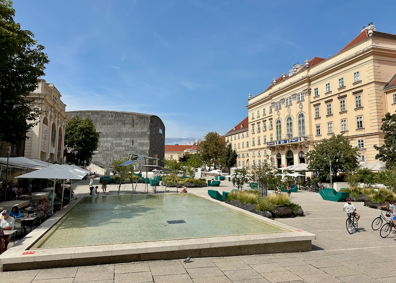 Reflecting pool in the center of a pedestrian plaza lined by museums