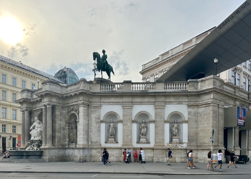 People walk past statues lining the Albertina museum in Vienna