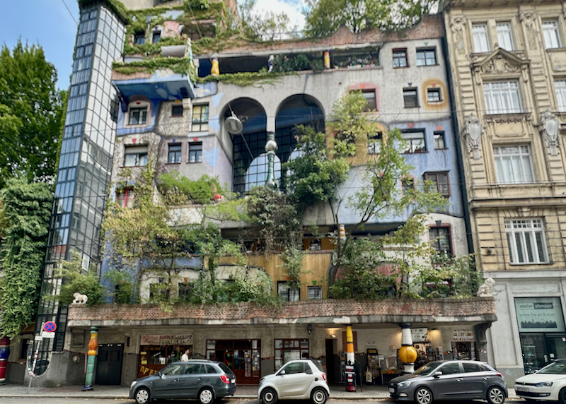 Colorful art-nouveau inspired building with trees growing on its many balconies