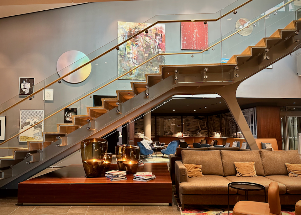 A cool modern stairway with glass sides ascends from a stylish hotel lobby