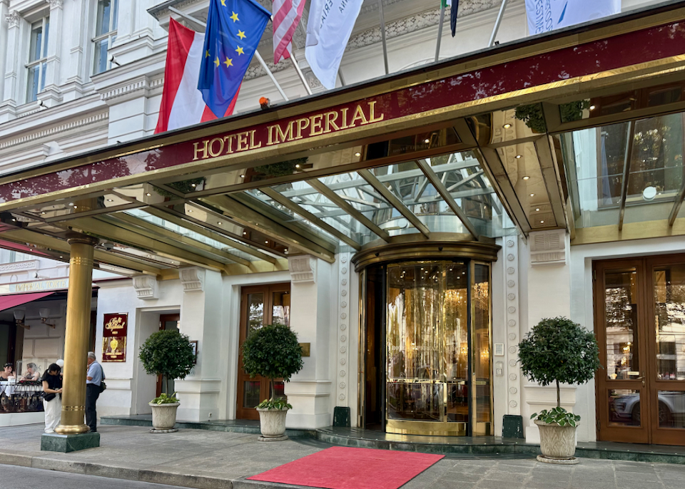 Entrance to a historic luxury hotel, with a mirrored awning and revolving gold doorway