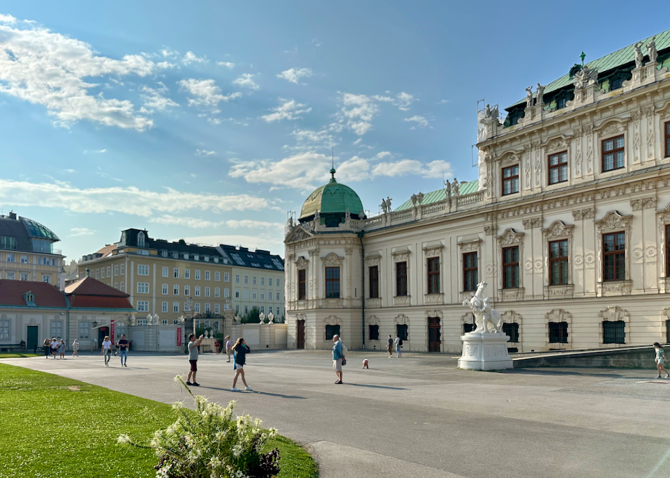 Toutists take photos in front of Belvedere Palace in Vienna.