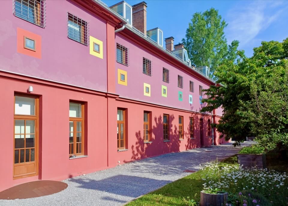 A hostel painted red and purple with pastel rainbow colored windows.