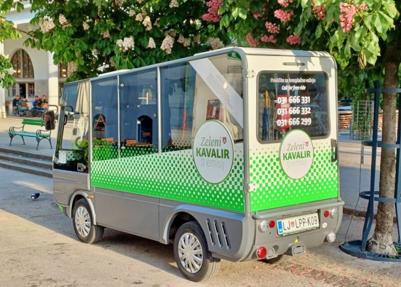 A small green minibus sits by the curb.