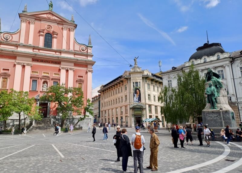 People stand in a huddle in the middle of a town square.