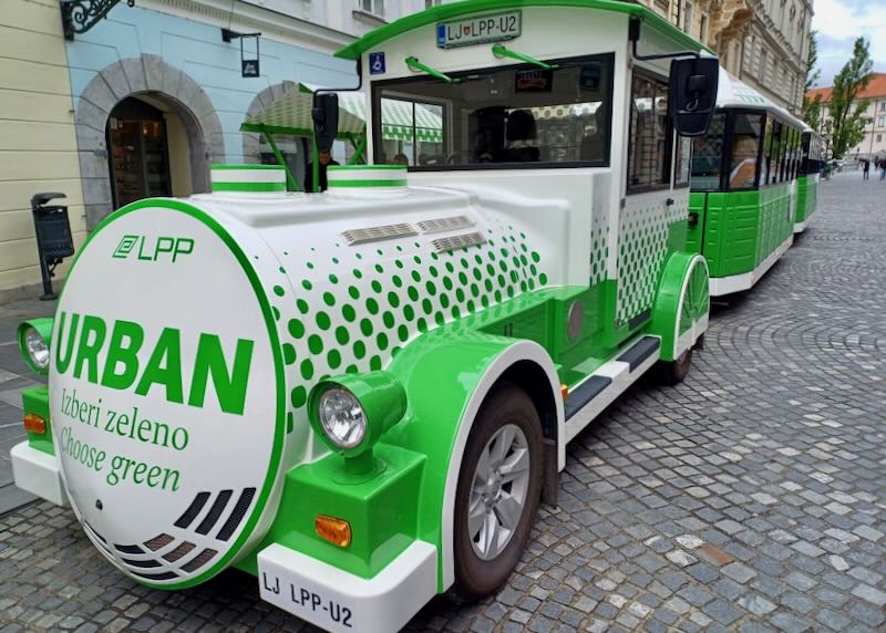An electric passenger shuttle sits waiting by the curb.